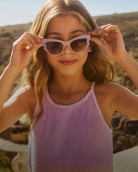 Young girl wearing pink sunglasses outdoors from Molo with a blurred natural background